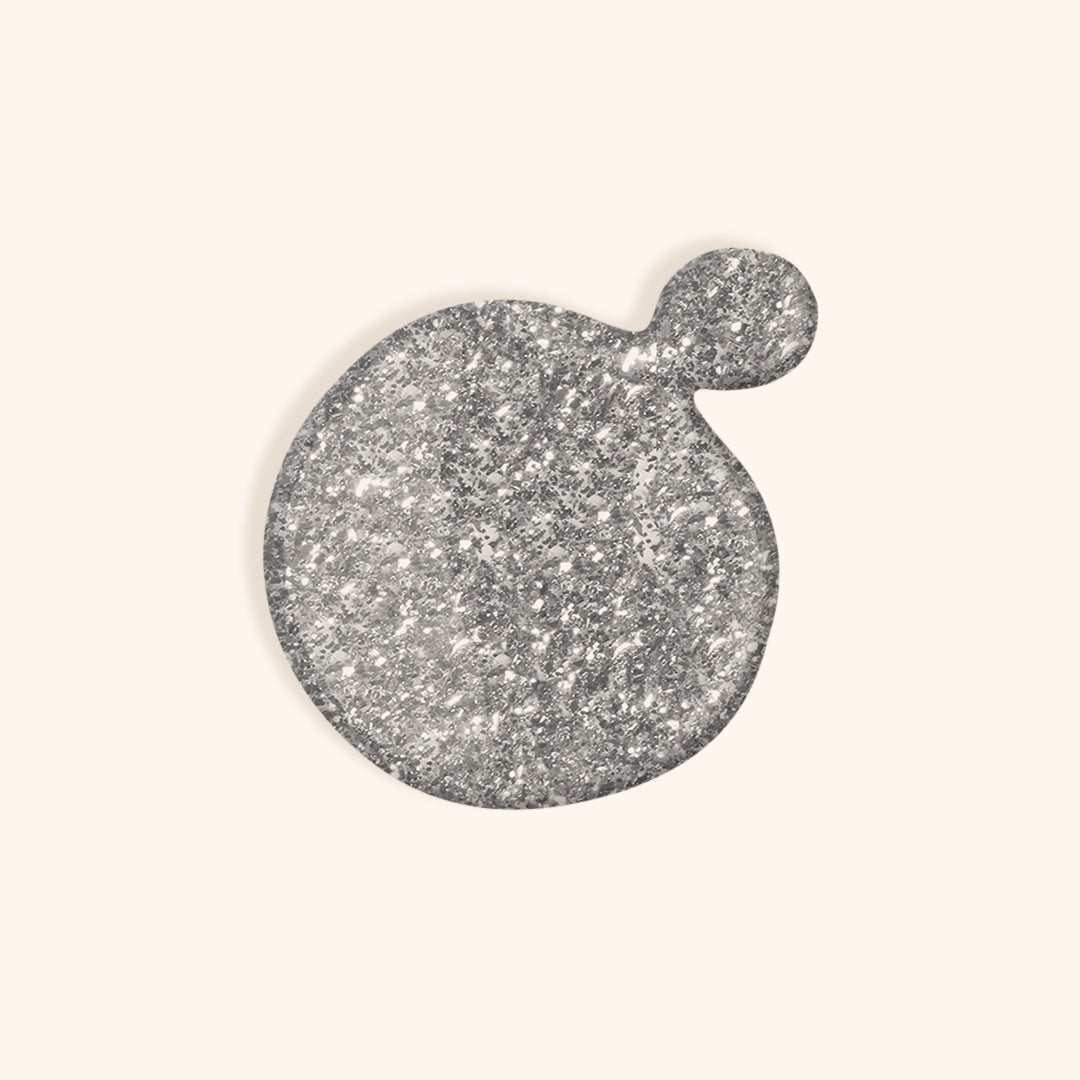 Silver shimmer gel nail polish in front of a beige background