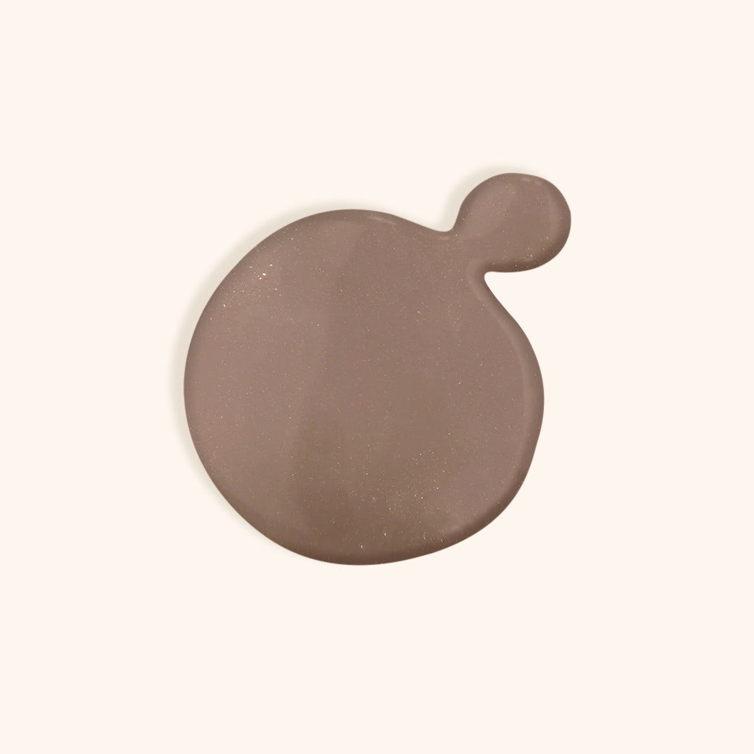 Shimmer brown nail polish in front of a beige background
