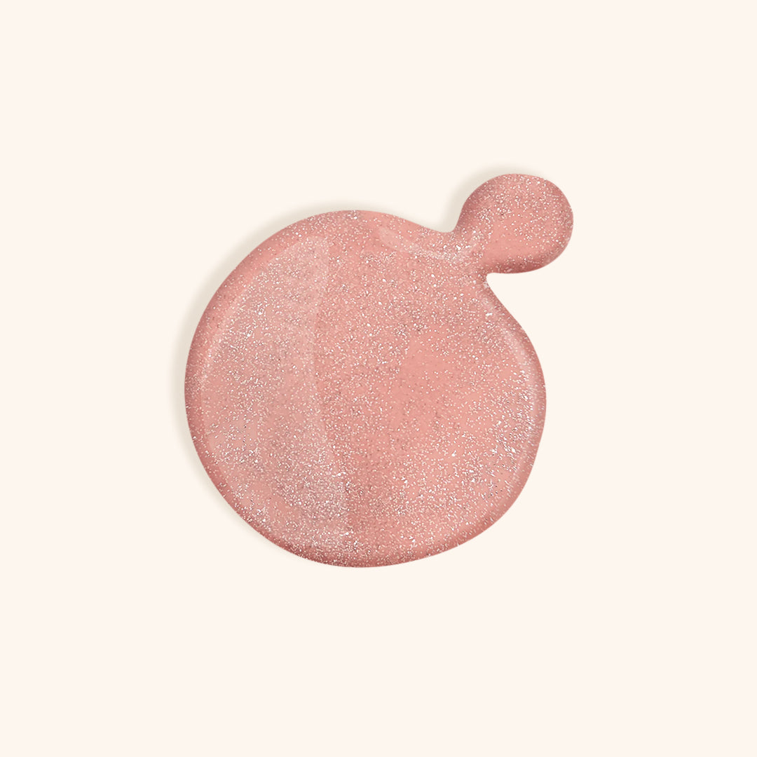 Bright nude nail polish with silver shimmer in front of a beige background