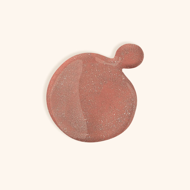 Deep shimmery pink nail polish in front of a beige background