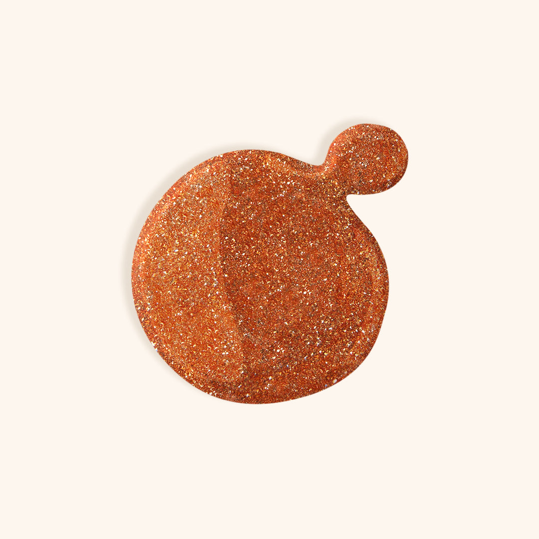 Glittery copper gel nail polish in white bottle